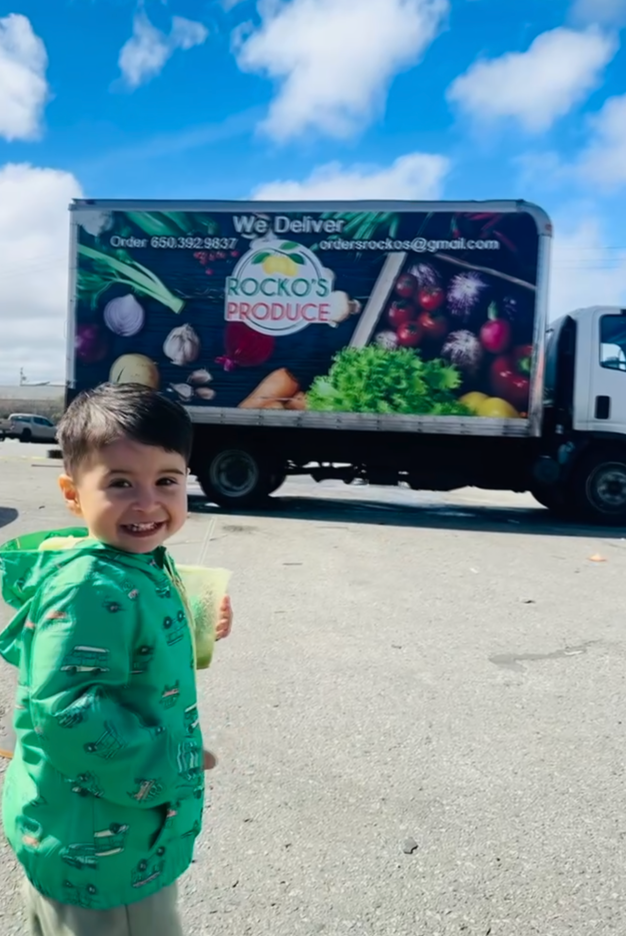 A young family member standing proudly in front of a Rocko’s Produce delivery truck