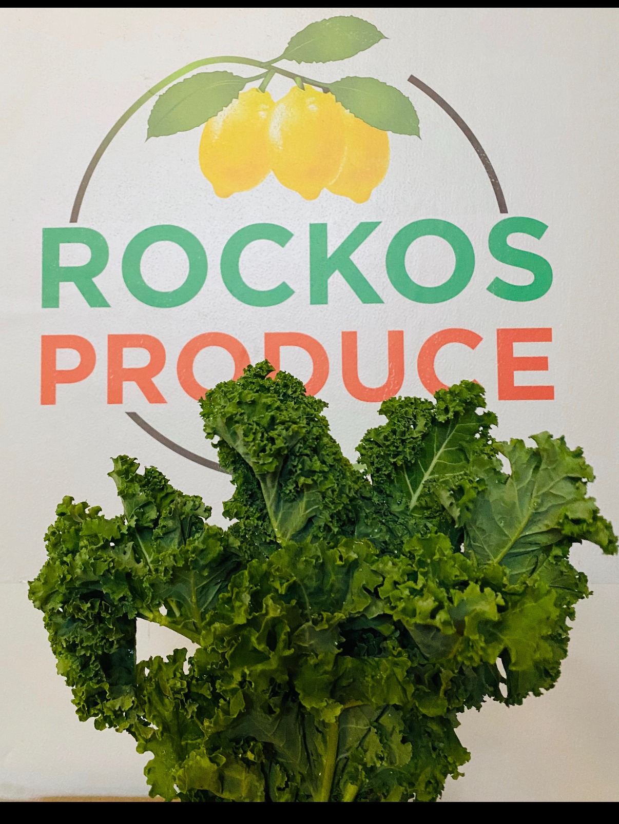 Fresh kale displayed in front of the Rocko’s Produce logo